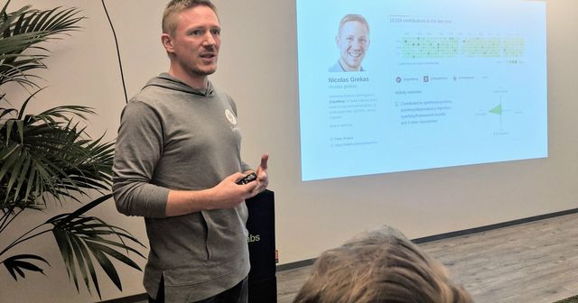 Nicolas Grekas in a grey Symfony hoodie standing in front of the audience