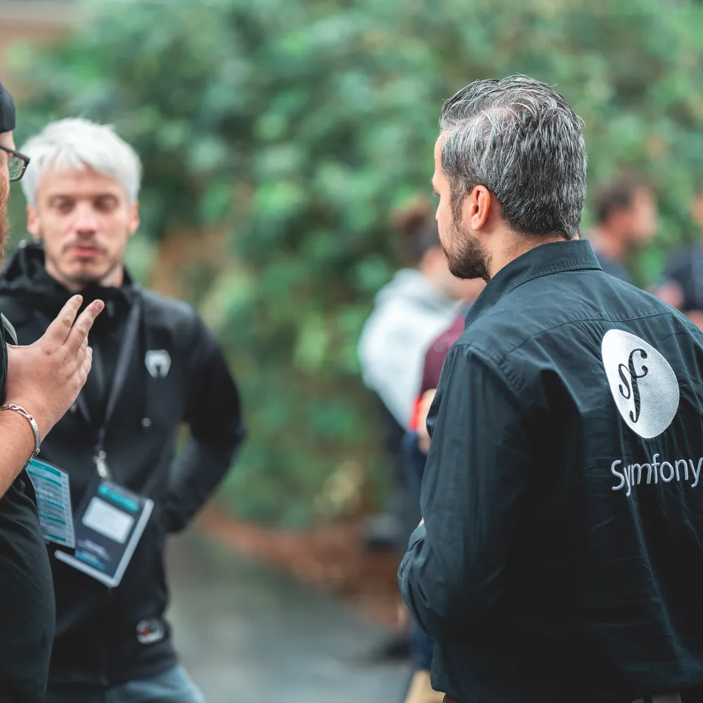 A group of developers talking one with a Symfony logo on his shirt