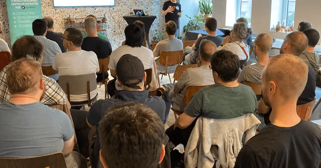 Nicolas Grekas facing the attendees sitting at the Symfony meetup in Brussels with fancy lights hanging