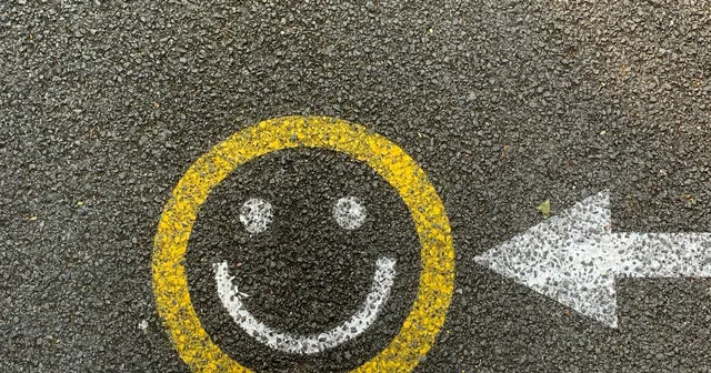 A yellow and white smiley on the ground with feets in sneakers