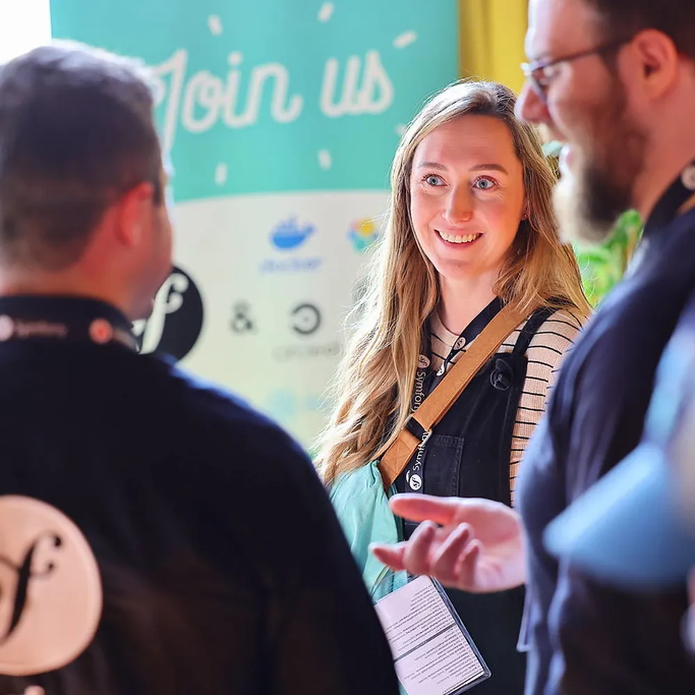 Visitors talking at the SensioLabs booth with a Symfony logo
