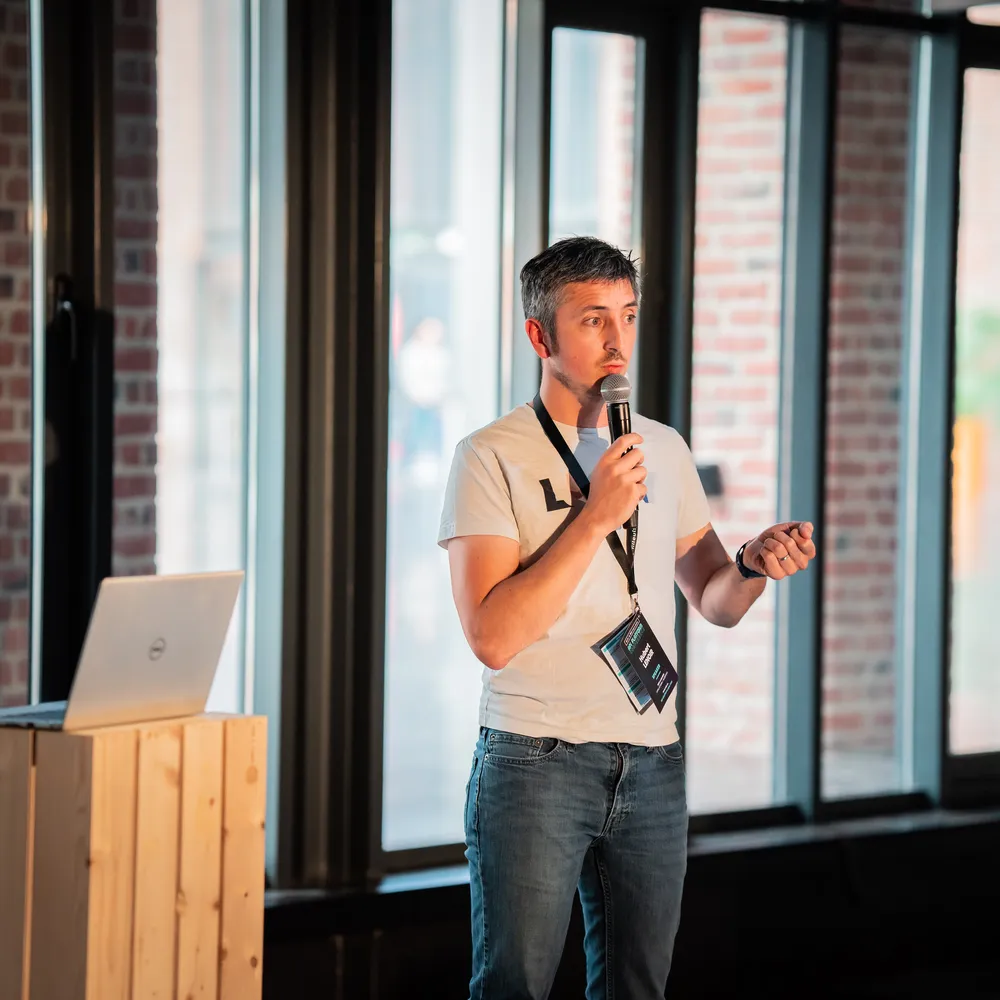 Hubert Lenoir standing with a mic and giving a talk at API PlatformCon
