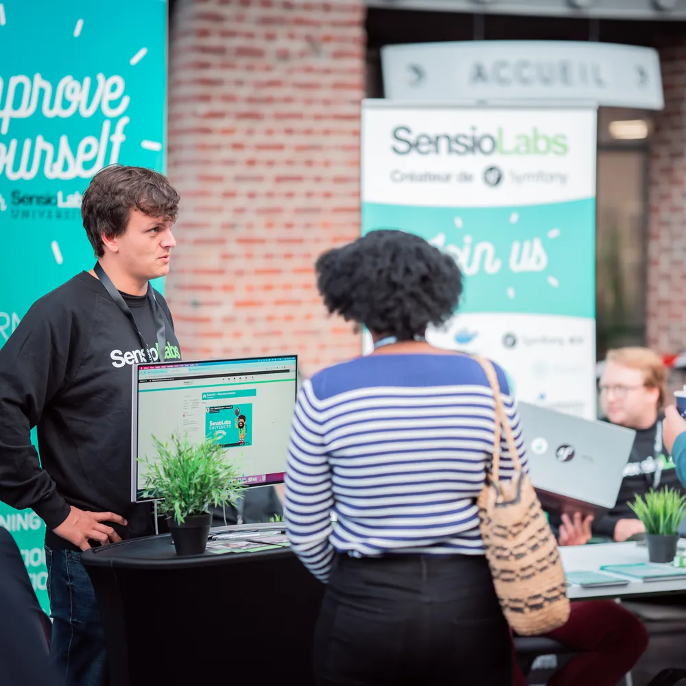 Sales Representative standing at his booth in front of an Improve Yourself roll up