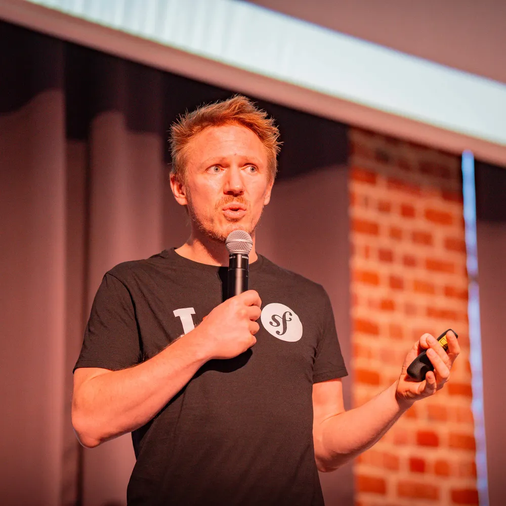 Nicolas Grekas speaking at a conference with a tee-shirt with a Symfony logo